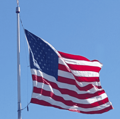 American flag waving against a clear blue sky.