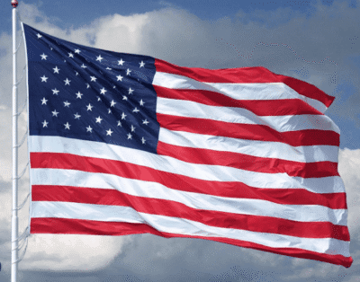 American flag waving against a partly cloudy sky.